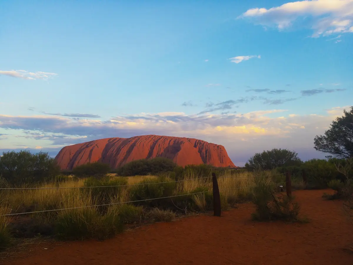 Uluru at sunset seen across the desert scrub